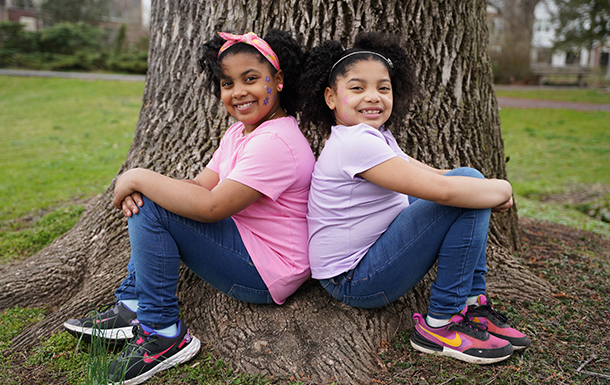 two sisters back to back at a tree