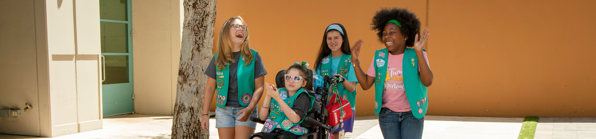  two girls wearing girl scout hoodie and jean jacket hugging and laughing 
